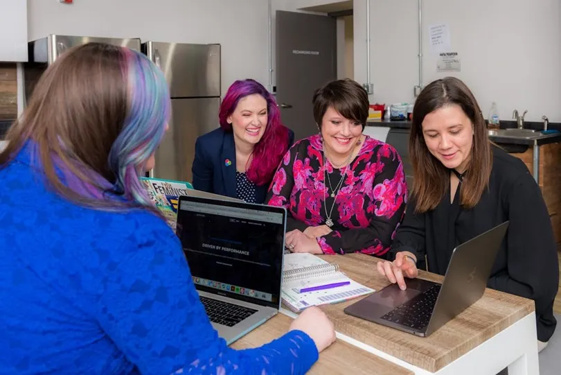 A group of employees seated at a table in an office, collaborating on enhancing data-driven decision-making