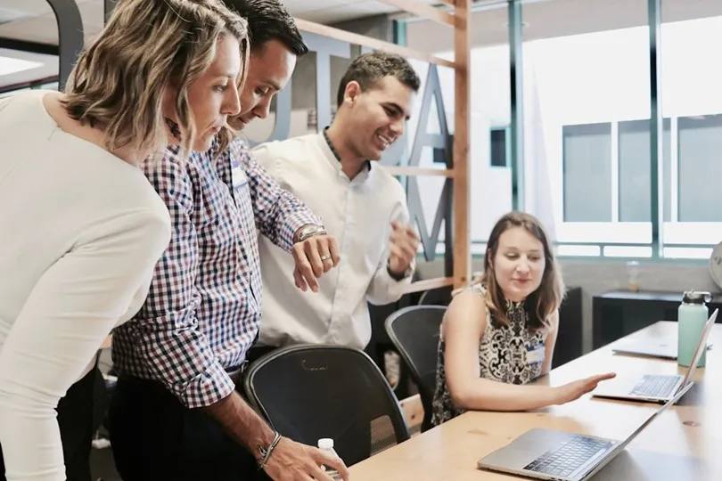 A group of employees in an office setting, using enterprise search software and discussing the impact of quick information retrieval